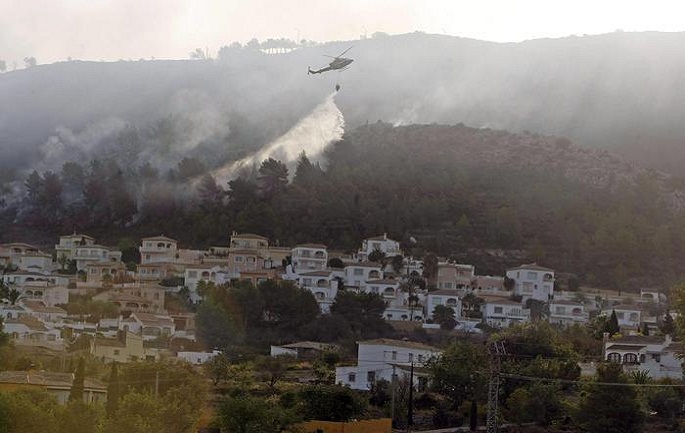epa05524975 A helicopter drops a fire retardant load over Villes del Vent in Benitatxell, on the Costa Blanca south of Valencia, Spain, on 05 September 2016. The fire, declared the previous day, has reached Xabia municipality forcing hundreds of evacuations.  l  EPA/MORELL
